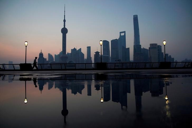 FILE PHOTO: A security guard walks on the bund in front of the financial district of Pudong in Shanghai