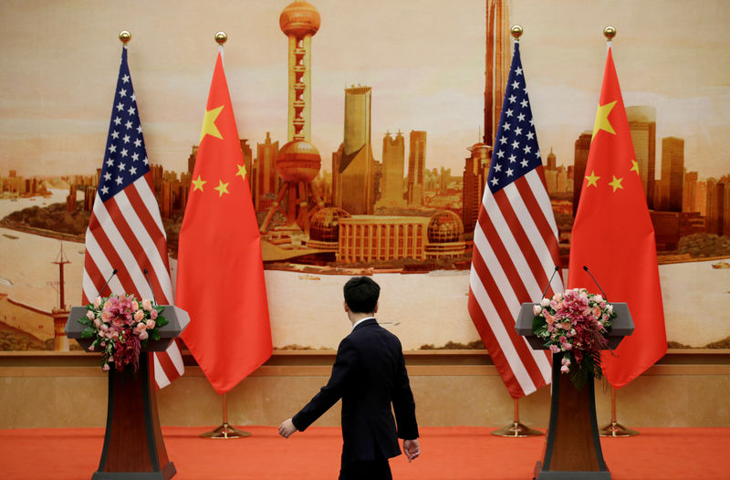 FILE PHOTO: A staff member walks past U.S. and Chinese flags placed for a joint news conference in Beijing