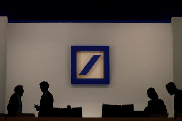 FILE PHOTO: People are silhouetted next to the Deutsche Bank's logo prior to the bank's annual meeting in Frankfurt