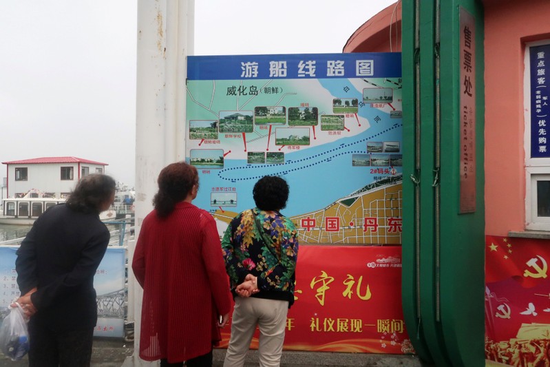 Chinese tourists look at a map detailing the route of a boat tour on the Yalu River, which separates North Korea and China, at a ticket office in Dandong