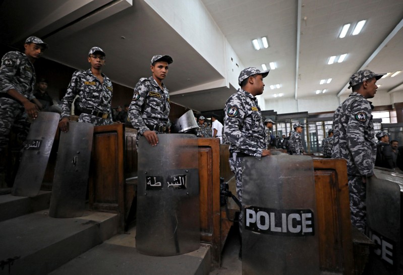Police stand guards during a court session in which 739 people are being tried for participating in a 2013 sit-in in support of the Muslim Brotherhood. in Cairo