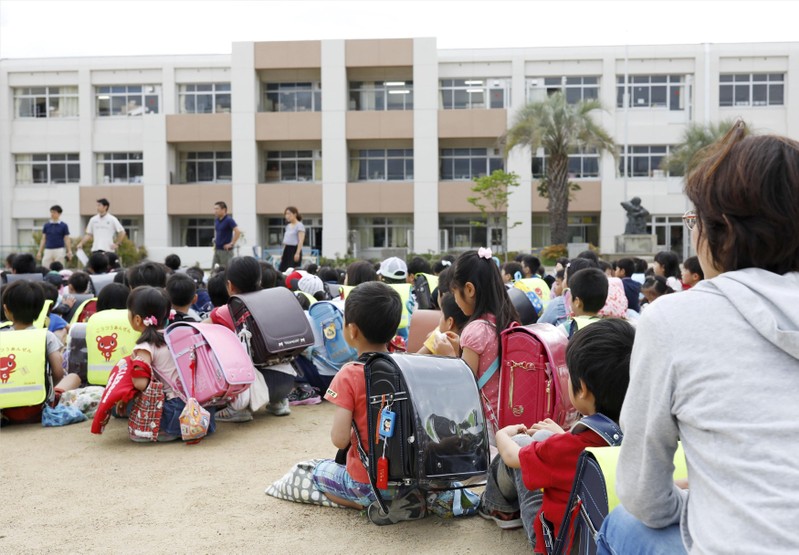 Students sit on a playground after they were evacuated from school building after an earthquake at Ikeda elementary school in Ikeda, Japan