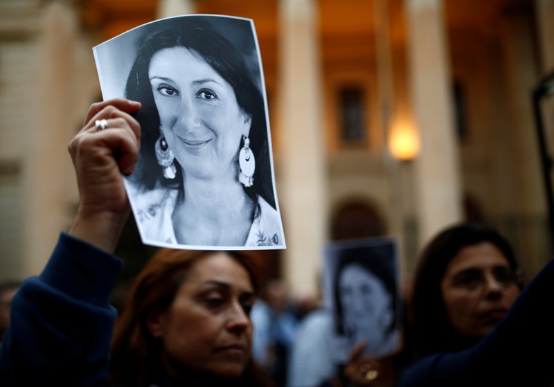 People hold up pictures of assassinated anti-corruption journalist Daphne Caruana Galizia during a vigil and demonstration marking seven months since her murder in a car bomb, at her makeshift memorial outside the Courts of Justice in Valletta