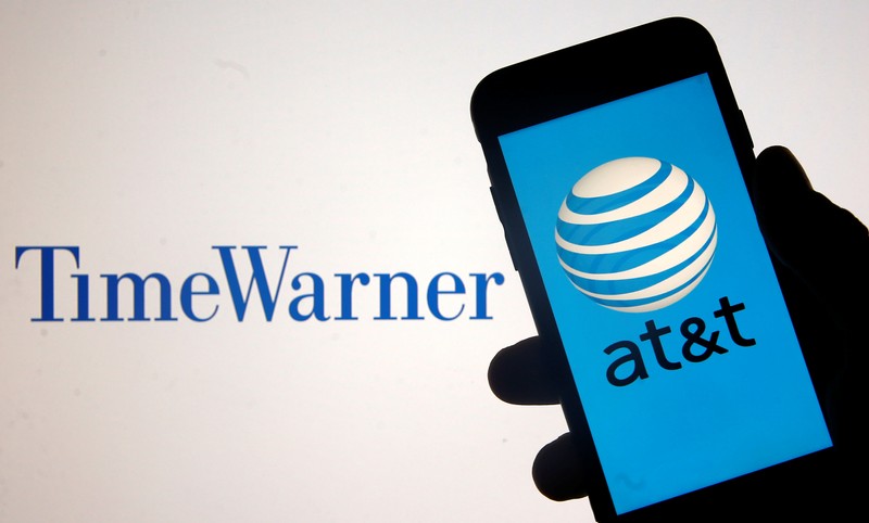 Smartphone with AT&T logo is seen in front of displayed Time Warner logo in this picture illustration