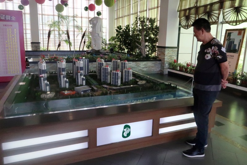 Brothers Holdings Managing Director T.C. Koh stands next to a model of Singapore City inside a property showroom in Dandong