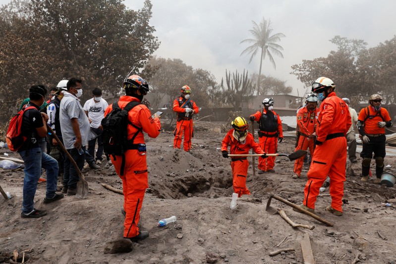 Mexican rescue workers search for the family of Eufemia Garcia, 48, who lost 50 members of her family during the eruption of the Fuego volcano, in San Miguel Los Lotes