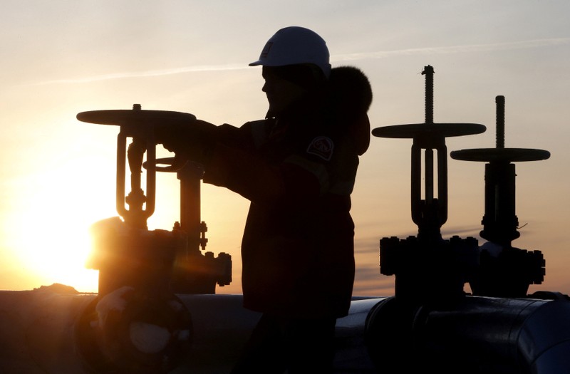 FILE PHOTO: Worker checks valve of oil pipe at Lukoil company owned Imilorskoye oil field outside West Siberian city of Kogalym