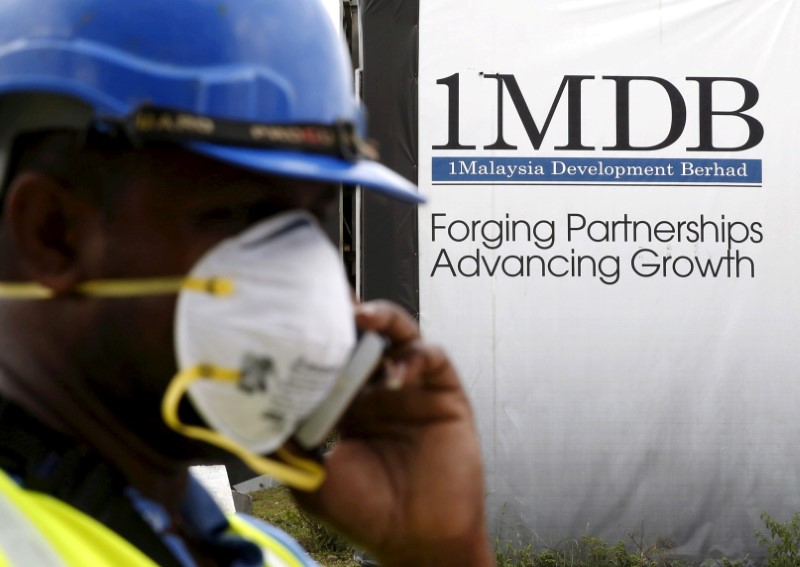 FILE PHOTO: A construction worker talks on the phone in front of a 1Malaysia Development Berhad (1MDB) billboard