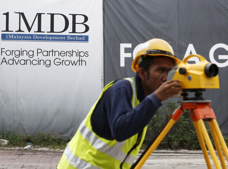A construction worker works in front of a 1Malaysia Development Berhad (1MDB) billboard at the Tun Razak Exchange development in Kuala Lumpur, Malaysia