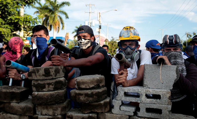 Demonstrators stand behind a barricade during clashes with riot police during a protest against Nicaragua's President Daniel Ortega's government in Managua