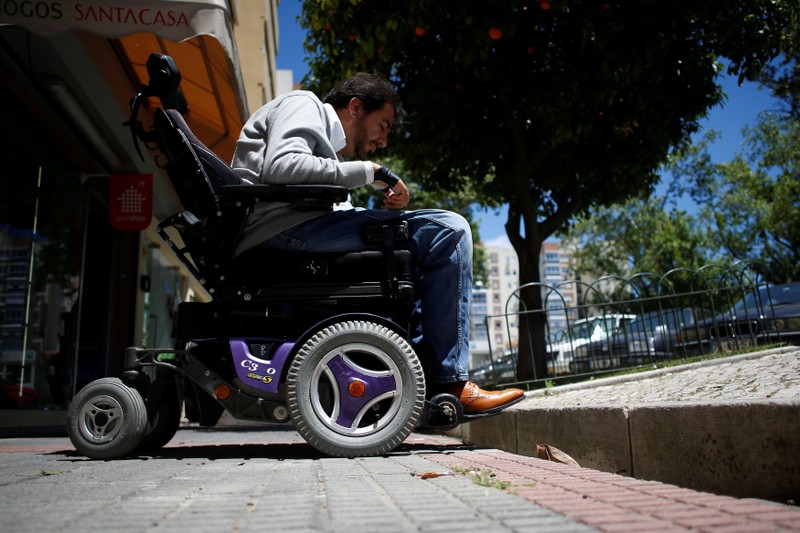 Wheelchair user Ricardo Teixeira demonstrates being unable to proceed to the sidewalk, in Lisbon