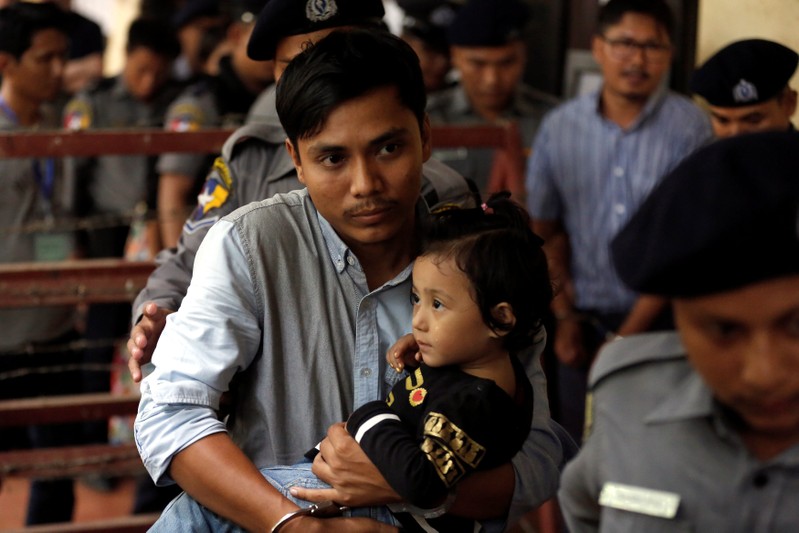 Detained Reuters journalist Kyaw Soe Oo carries his daughter Moe Thin Wai Zin while escorted by police to lunch break during a court hearing in Yangon