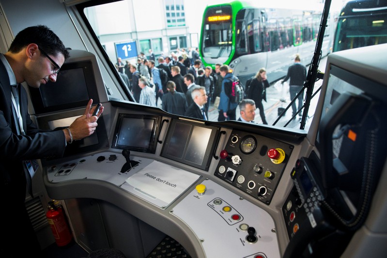 A man takes a picture of the cockpit of a Desiro City passenger train by Siemens Mobility at the InnoTrans railway technology trade fair in Berlin