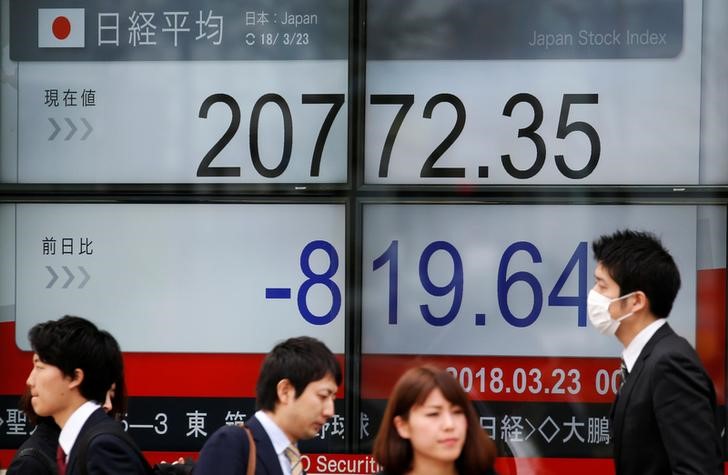 People walk past an electronic board showing Japan's Nikkei average outside a brokerage in Tokyo