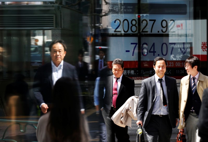 People walk past an electronic board showing Japan's Nikkei average outside a brokerage in Tokyo