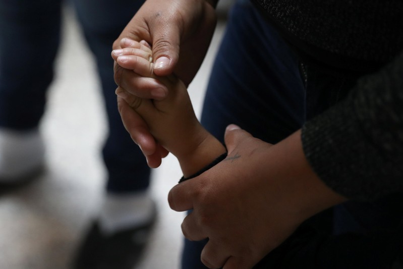 A woman holds a child's hand as undocumented immigrant families are released from detention at a bus depot in McAllen