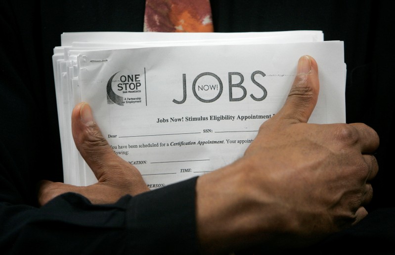 FILE PHOTO: Man carrying a stack of job listings listens to a discussion at the One Stop employment center in San Francisco