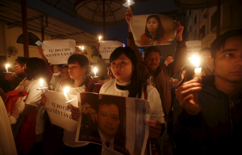 Vu Minh Khanh holds image of her husband Nguyen Van Dai as Catholics hold candles and images of Dai's assistant Le Thu Ha during a mass prayer for Dai and Ha at Thai Ha church in Hanoi