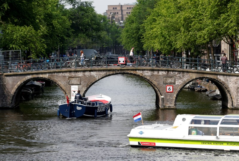 FILE PHOTO: Tourists boats pass on a canal in Amsterdam