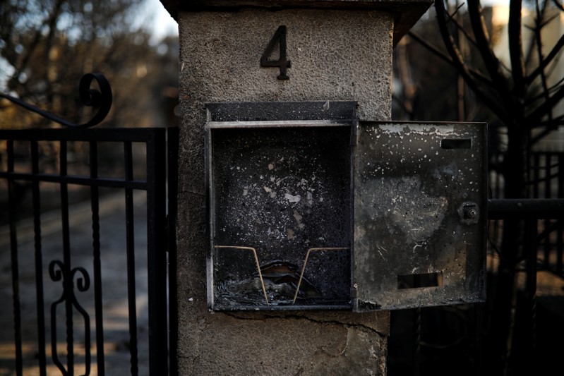 A burnt mailbox is seen at the entrance of a destroyed house following a wildfire at the village of Mati