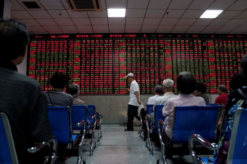 Investors look at an electronic board showing stock information at a brokerage house in Shanghai