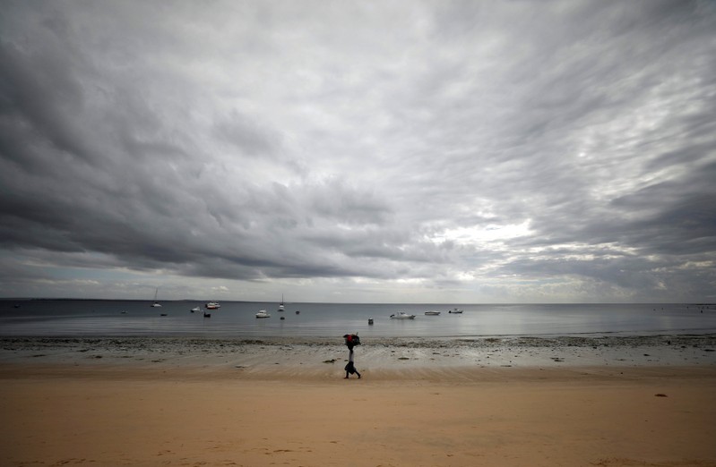 Subsistence fisherman walks along an empty beach in Pemba