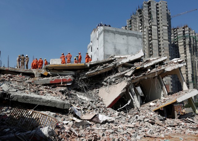 Rescue workers look for survivors amidst the rubble at the site of a collapsed residential building at Shah Beri village in Greater Noida