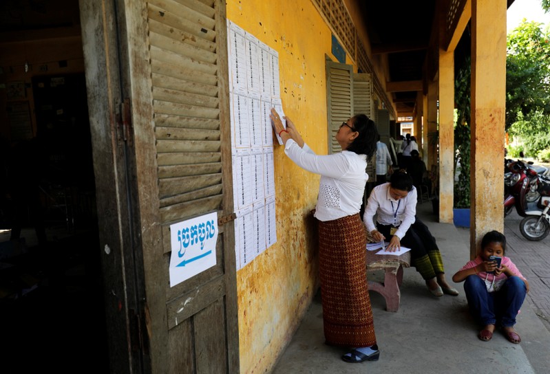 An election worker posts a voter list outside a polling booth located at a school in Phnom Penh