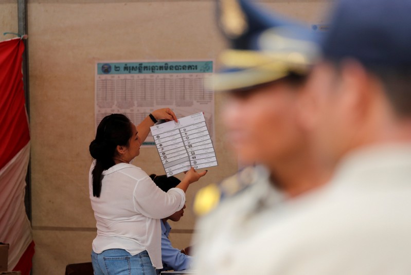 Police provide security at a polling station as an official counts ballots in Cambodia's general election, at a polling station in Phnom Penh, Cambodia
