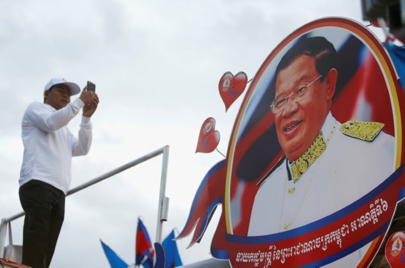A supporter of the ruling Cambodian People's Party (CPP) uses a mobile phone to photograph a portrait of CPP president Hun Sen during an election campaign in Phnom Penh