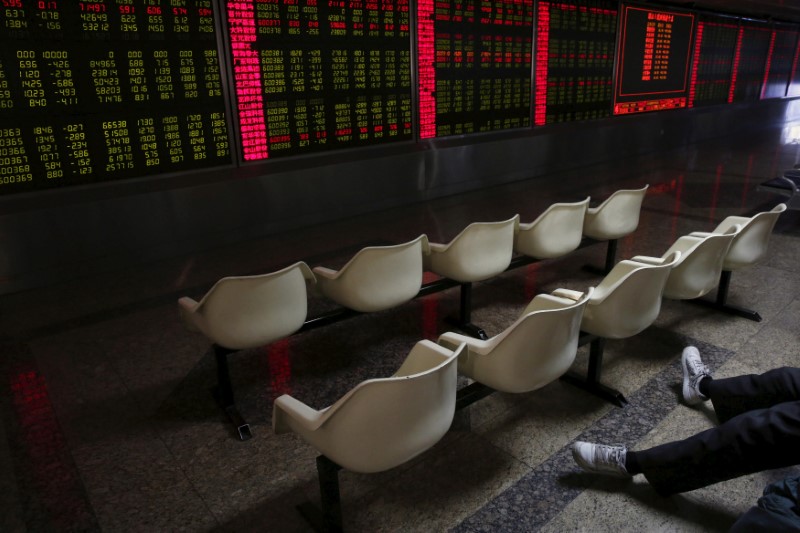 FILE PHOTO: A man's legs are pictured as he looks at an electronic board showing stock information is pictured at a brokerage house in Beijing