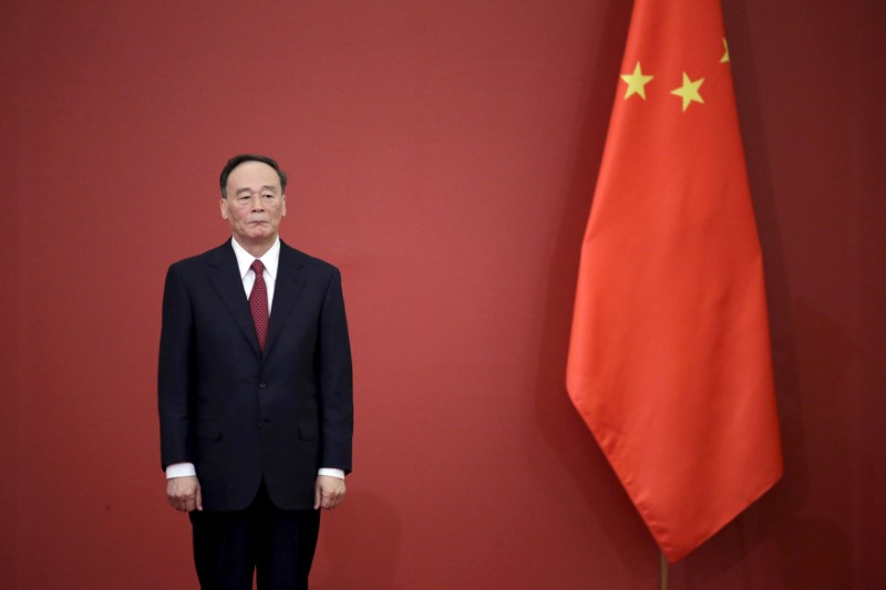 FILE PHOTO: China's Politburo Standing Committee member Wang Qishan stands next to a Chinese flag in Beijing