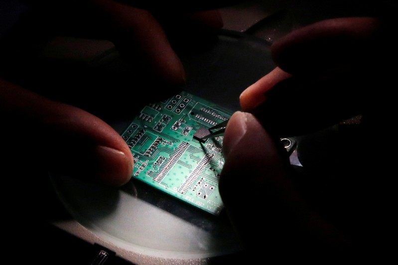 FILE PHOTO: A researcher plants a semiconductor on an interface board which is placed under a microscope during a research work to design and develop a semiconductor product at Tsinghua Unigroup research centre in Beijing