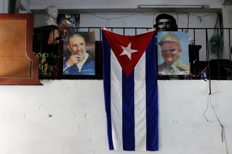 The Cuban flag hangs next to the photographs of late Cuba's President Fidel Castro and his brother, Cuba's former President Raul Castro, in Havana
