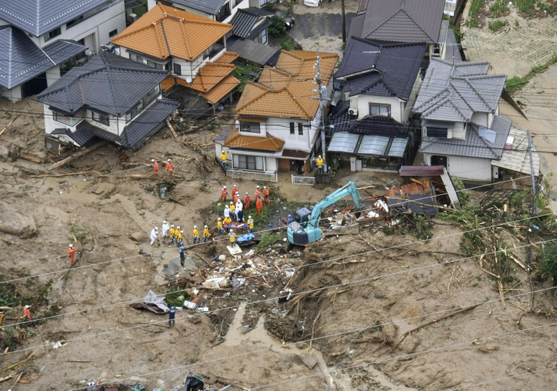 Rescue workers are seen next to houses damaged by a landslide following heavy rain in Hiroshima