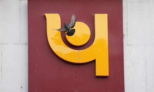 FILE PHOTO: A pigeon flies past the logo of Punjab National Bank outside a branch of the bank in New Delhi