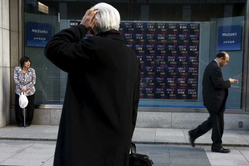 A man looks at an electronic board showing market indices outside a brokerage in Tokyo