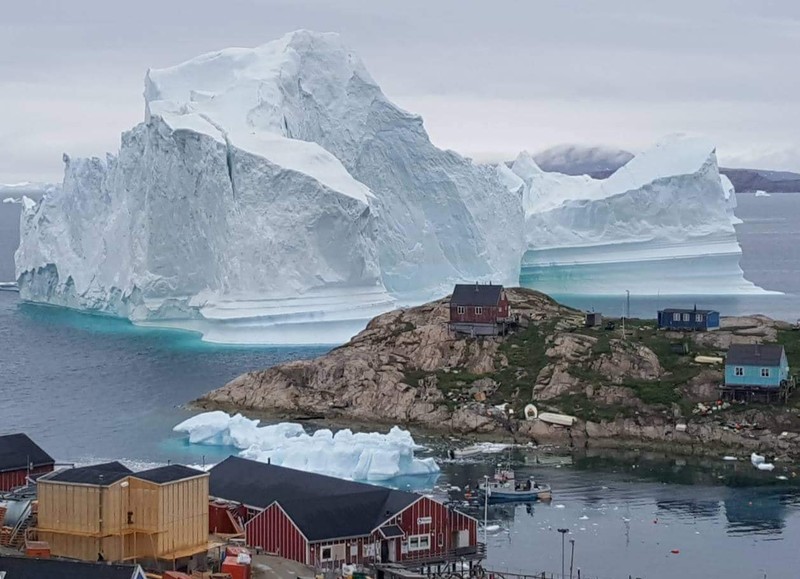 A giant iceberg is seen behind an Innaarsuit settlement