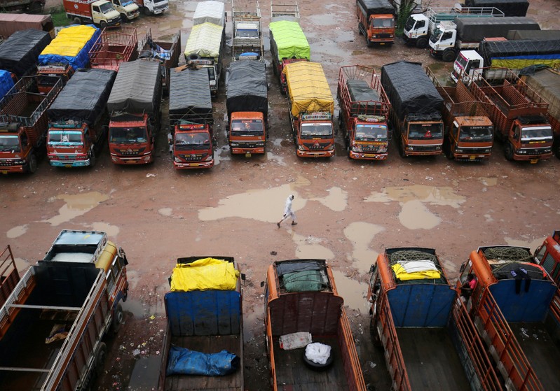 FILE PHOTO: A driver walks past parked trucks inside a depot during a nationwide strike in Ahmedabad