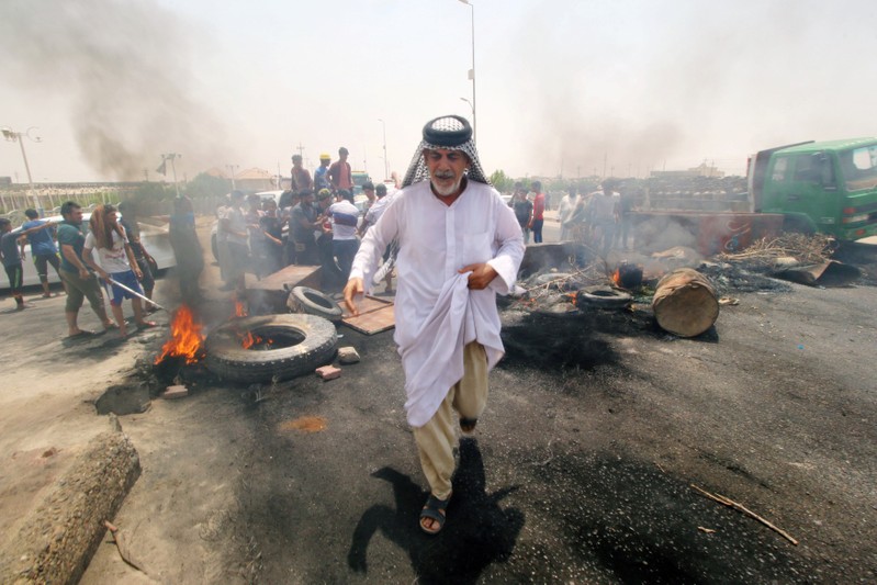 Iraqi protesters burn tires and block the road at the entrance to the city of Basra