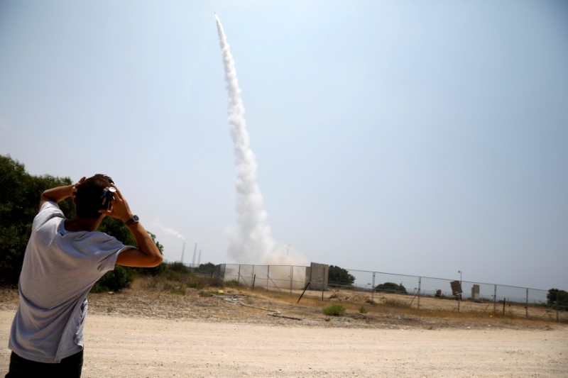 An Israeli man looks on as an Iron Dome launcher fires an interceptor rocket in the southern Israeli city of Ashkelon