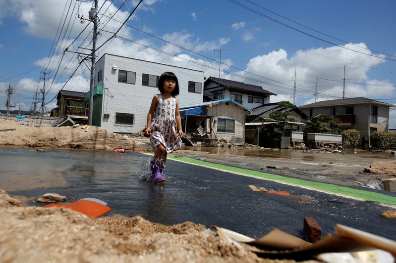 A local resident walks in a flood affected area in Mabi town in Kurashiki