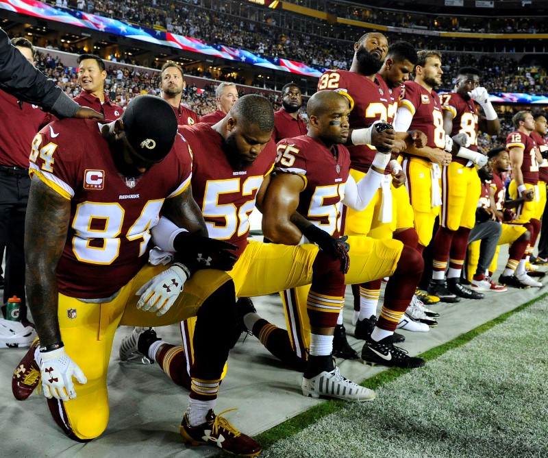 FILE PHOTO: Washington Redskins players kneel during the playing of the national anthem