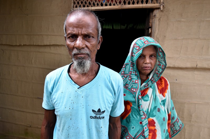 Abdul Suban, a farmer, and his wife pose for a photograph outside their home in Nellie village, in Morigaon district