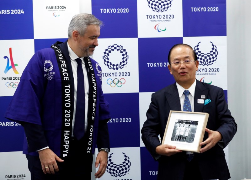 Paris 2024 Director General Etienne Thobois wearing a Japanese happi coat presents a photo of Japanese athletes taken at 1924 Paris Olympic Games to Toshiro Muto, Tokyo 2020 CEO, in Tokyo