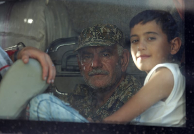 A fighter loyal to President Bashar al Assad and a child are seen in a bus as they are evacuated from the villages of al-Foua and Kefraya