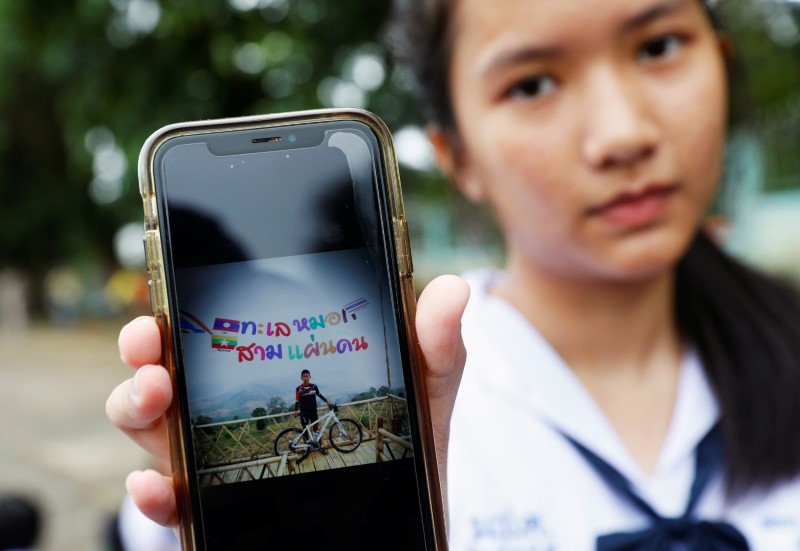 A student shows a photo of her classmate Prachak Sutham, 13, who is a member of an under-16 soccer team that went missing with their coach at a flooded cave, in Mae Sai Prasitsart school in the northern province of Chiang Rai