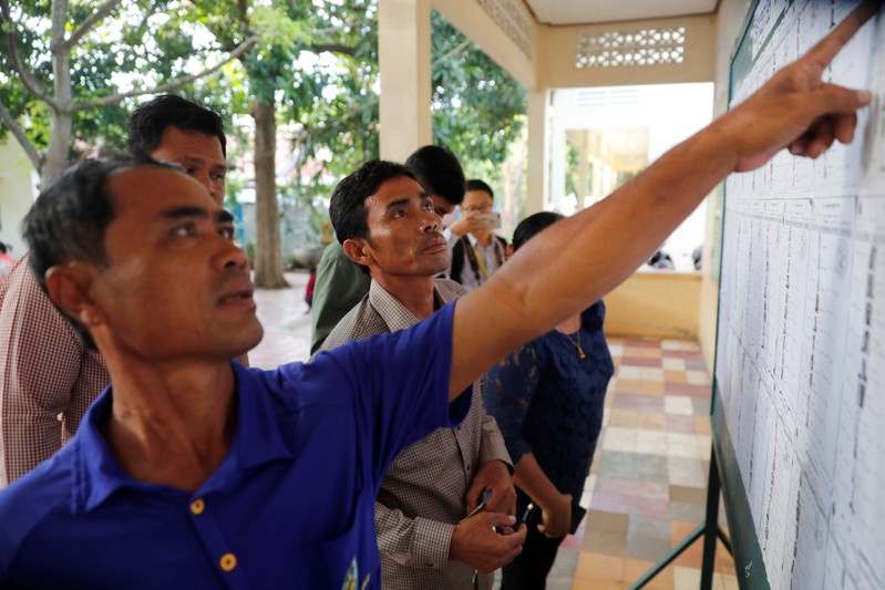Voters look at a voters list before the start of a general election in Takhmao