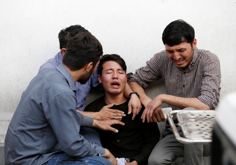 Afghan men mourn after a blast in a hospital in Kabul
