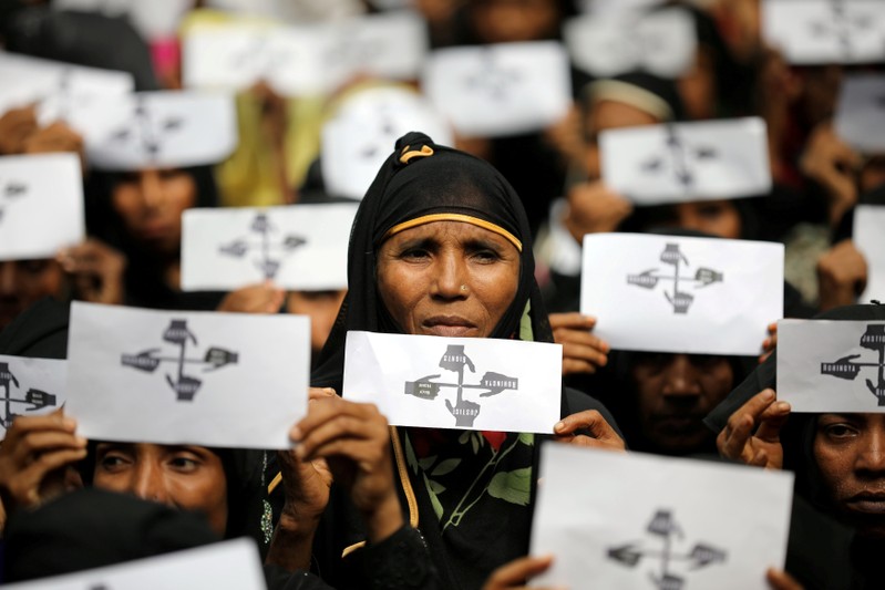 Rohingya refugee women hold placards as they take part in a protest at the Kutupalong refugee camp to mark the one-year anniversary of their exodus in Cox's Bazar